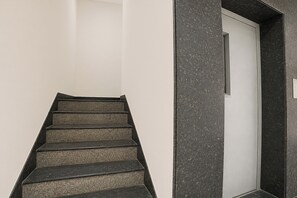 A staircase with a dark finish leading to a white door.