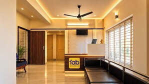 A hotel reception area with a reception desk, seating area, and a ceiling fan.