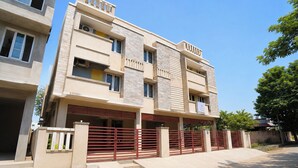 A multi-story residential building with a flat roof, balconies, and a gated entrance.
