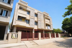 Un edificio residencial de varios pisos con techo plano, balcones y una entrada con portón.