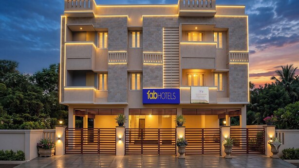 A modern hotel facade with a prominent sign, multiple balconies, and a gated entrance.