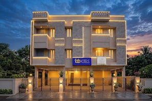 A modern hotel facade with a prominent sign, multiple balconies, and a gated entrance.