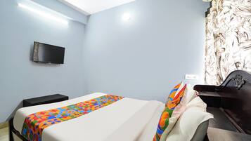 A bedroom with a bed, a television mounted on the wall, and a patterned wallpaper.