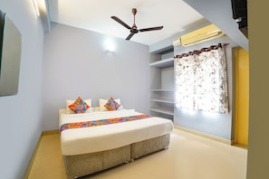 Quarto com cama, ventoinha no teto, janela com cortinas e prateleira embutida.