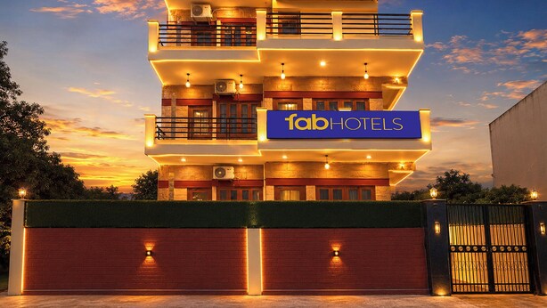 Un hotel de varios pisos con un letrero destacado que dice 'fabHOTELS' y una entrada con portones.