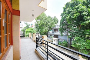 A balcony with a view of a residential area, a railing, and a hanging light fixture. - Fabhotel Maurya Residency (Gurugram)