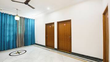A hotel corridor with a ceiling fan, two wooden doors with room numbers, and a patterned floor.