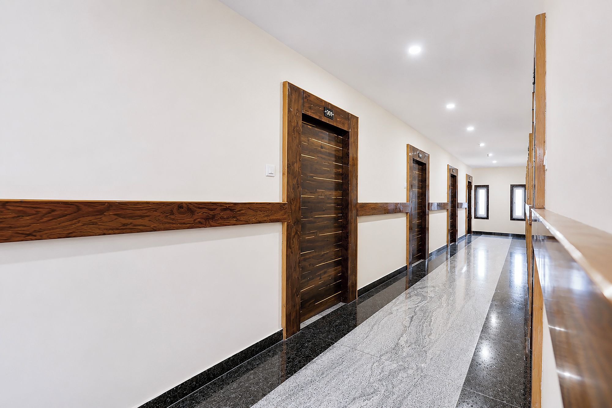 Un pasillo con puertas de madera y suelo de mármol.