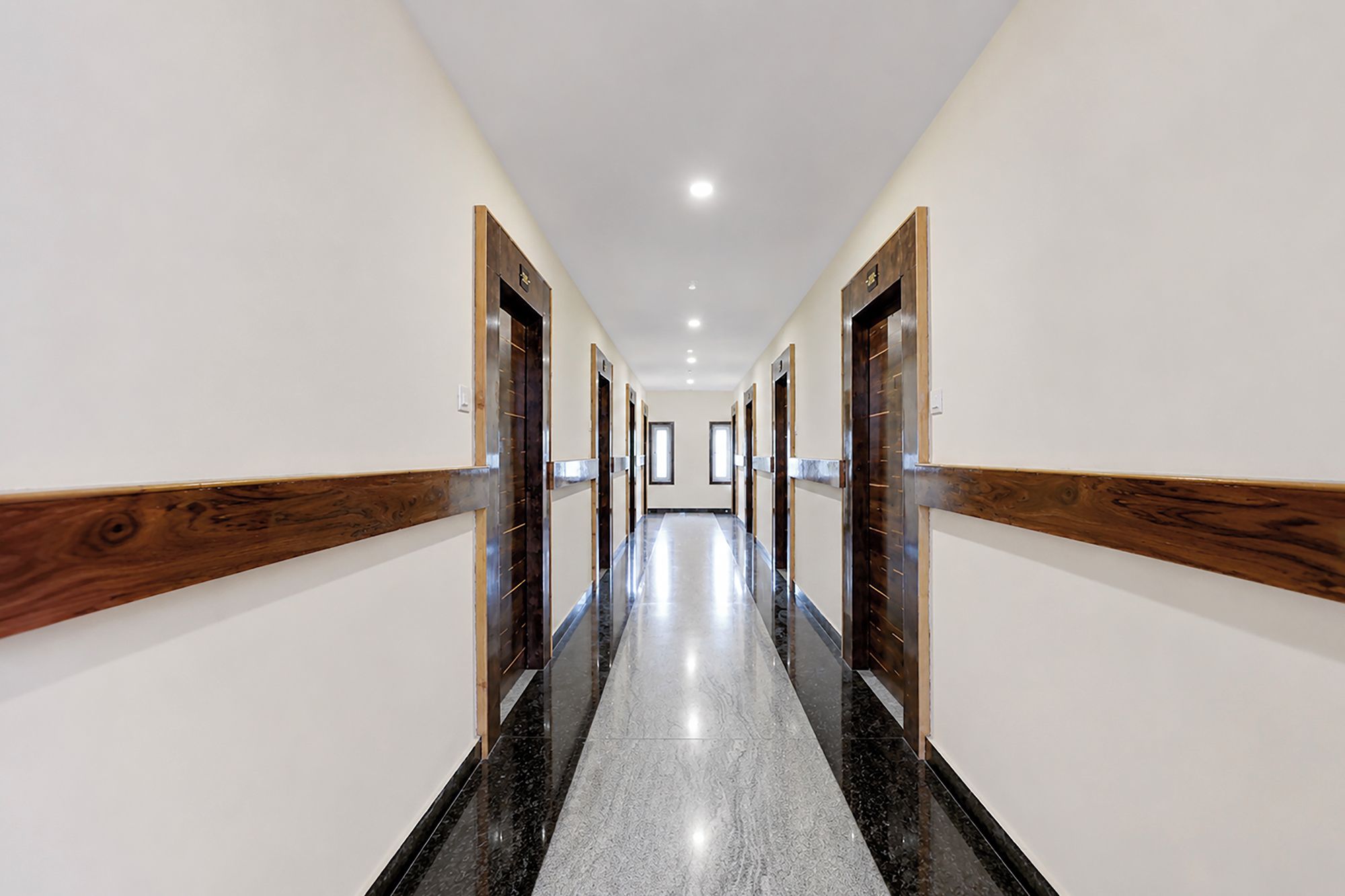 Un largo y estrecho pasillo con paneles de madera en las paredes y puertas, que conduce a varias habitaciones.