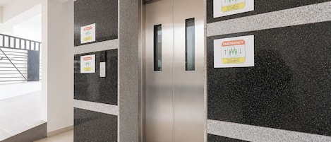 Un ascensor con señalización de emergencia y una puerta metálica.