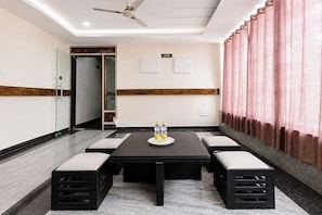 Een vergaderzaal met een tafel, stoelen en een plafondventilator.