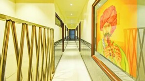 A hallway with a long corridor, a framed artwork on the wall, and a patterned curtain. - Fabhotel Ritz Residency (Jaipur)