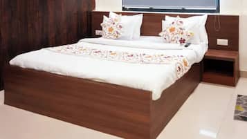 Ein Doppelbett mit hölzernem Gestell, weißer Bettwäsche und Kissen mit Blumenmuster.