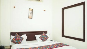 A hotel room with a bed, a bedside table, a wall-mounted air conditioner, and a framed picture. - Fabhotel Ritz Residency (Jaipur)