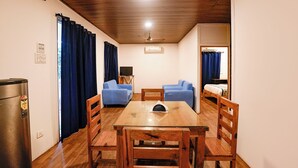 Una habitación compacta con techo de madera, una mesa de comedor con sillas, un sofá, una cama y una televisión.