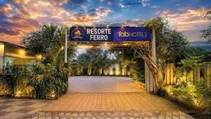 Un letrero que dice 'Resorte Ferro' con la marca 'fab hotels', rodeado de exuberante follaje y un acceso pavimentado.