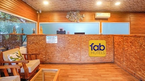 Una zona de recepción con un mostrador de madera, un cartel de 'fab hotels' y vistas al exterior a través de un ventanal.