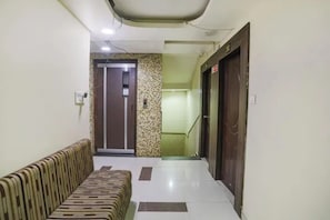 A hallway with a patterned sofa, a door, and a wall with a decorative tile pattern. - Fabhotel Ashoka Palace (Bhopal)