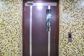 Un ascensor con pantalla digital, un pomo metálico y un panel decorativo.