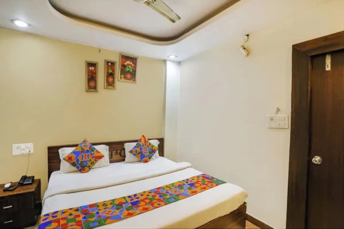 A hotel room with a bed, a nightstand, a door, and a ceiling fan.