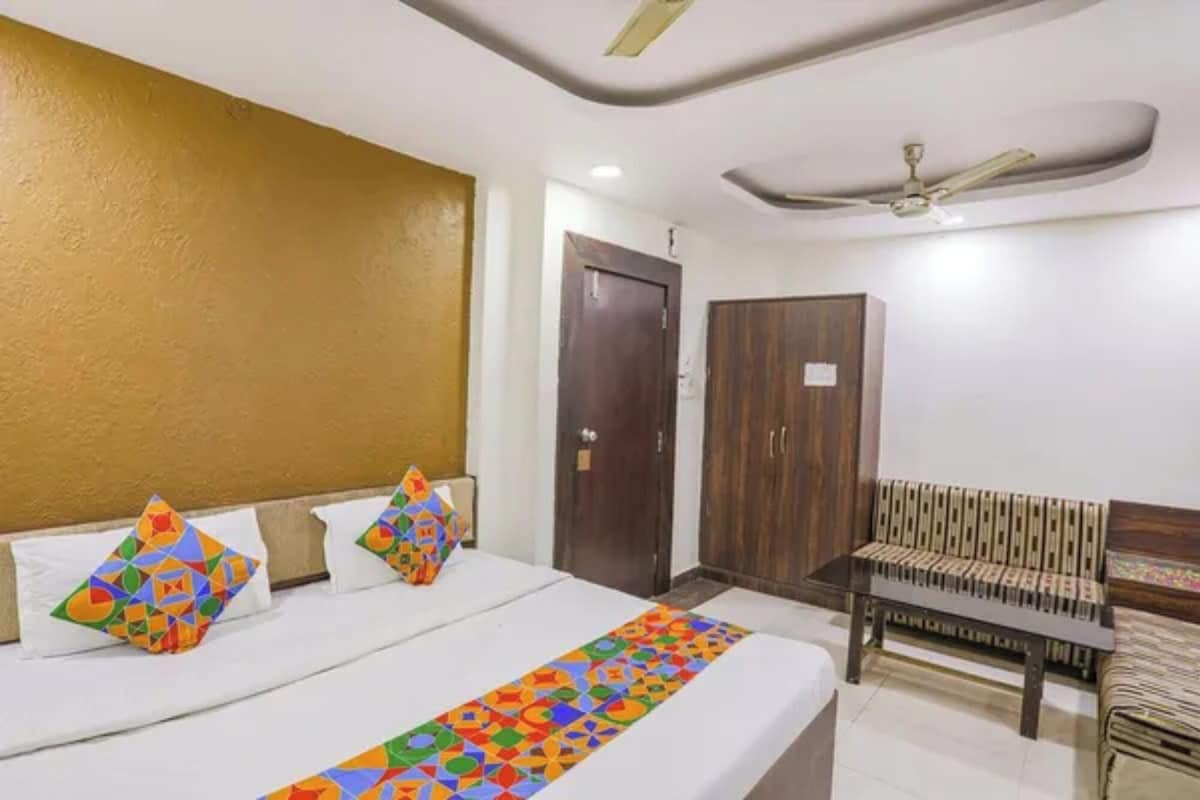 A hotel room with a bed, a desk, a wardrobe, and a ceiling fan.