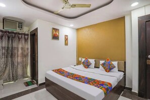 A hotel room with a bed, a ceiling fan, a window with curtains, and a door. - Fabhotel Ashoka Palace (Bhopal)
