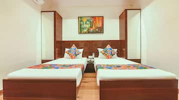Habitación de hotel con dos camas, cabecero de madera, un cuadro sobre las camas y una pequeña mesa entre ellas.