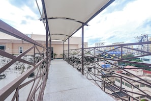 A balcony with a metal railing, a concrete floor, and a view of surrounding buildings.