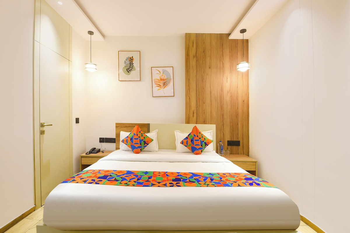 Una habitación de hotel con una cama, mesitas de noche, un panel de pared de madera y obras de arte en la pared.