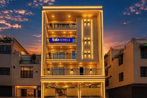 Un hotel de varios pisos con un llamativo letrero 'fab hotels', balcones e iluminación en la fachada.