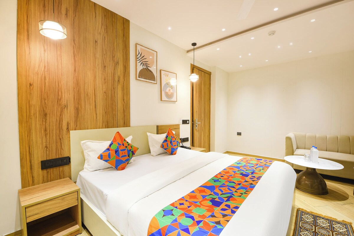 Una habitación de hotel con cama, mesitas de noche, una pequeña mesa redonda y un sofá.