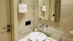 A modern bathroom with a white sink, a mirror, and a wooden cabinet. - Fabhotel Prime Da Marion (New Delhi)