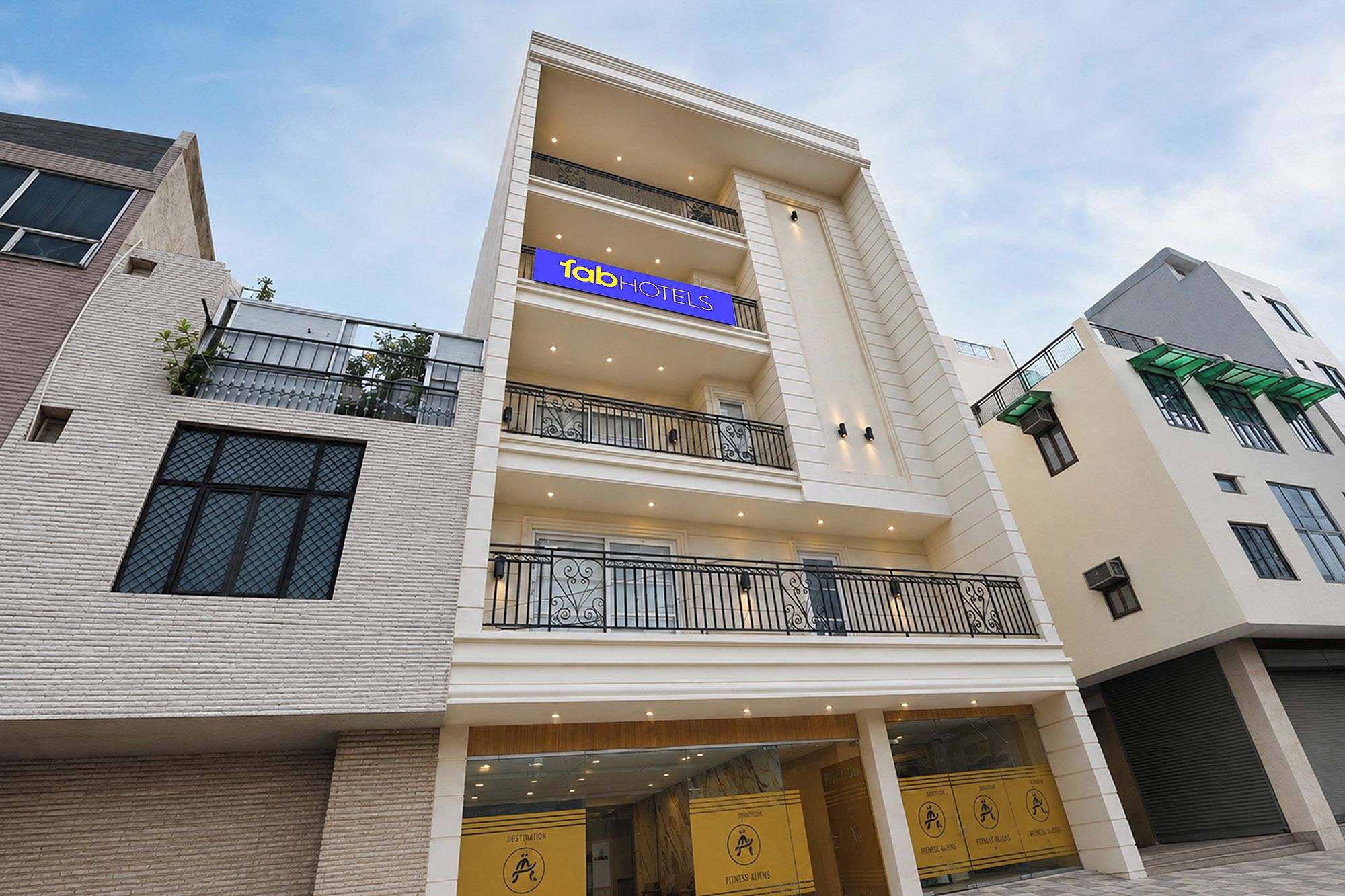 A hotel with a blue sign, multiple balconies, and a ground-level entrance with a yellow sign.