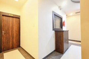 Corredor com porta de madeira identificada com o número '101', um extintor de incêndio fixado na parede e um pequeno armário de madeira.