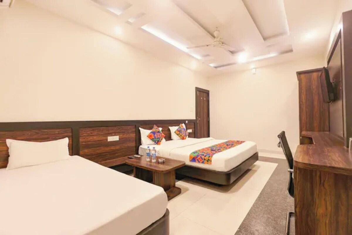 Habitación de hotel con dos camas, un escritorio, una silla y un televisor.