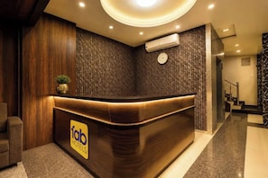Uma receção de hotel com acabamento em madeira, um relógio e uma unidade de ar condicionado acima.