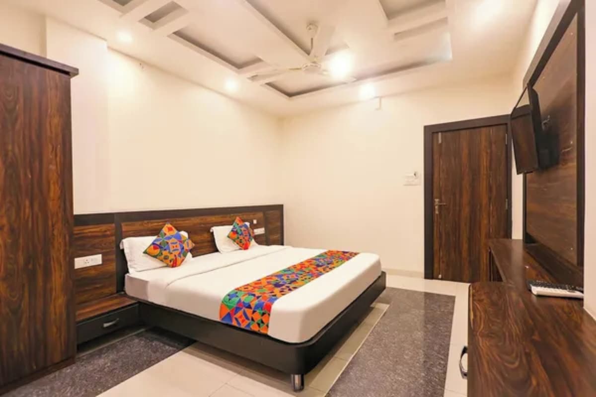 Un dormitorio con una cama, armario de madera y televisor.