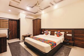 Quarto de hotel com cama, mesas de cabeceira, guarda-roupa e aparelho de ar condicionado.