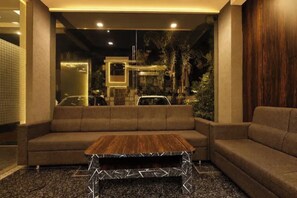 Um interior moderno com sofá seccional, mesa de centro de madeira e vista para o horizonte urbano através de uma grande janela.