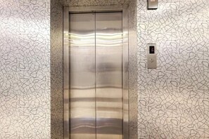 Un ascensor con interior metálico y diseño de pared con motivos.