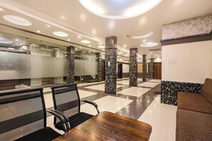 Um lobby moderno com piso xadrez, pilares estampados em preto e branco e uma mesa de recepção de madeira.