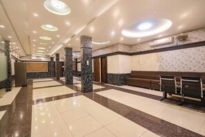Um hall amplo com piso de mármore, balcão de recepção e área de estar com cadeiras.