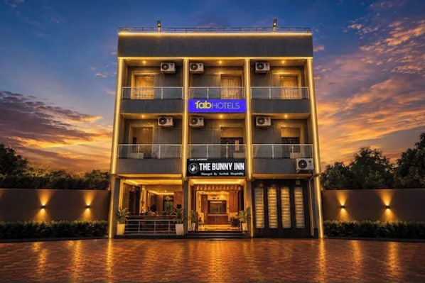 Un edificio de varios pisos con un cartel que indica 'fabHOTELS' y 'THE BUNNY INN', señalando un hotel.