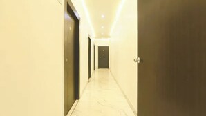 Un pasillo con puertas a ambos lados, que conduce a un cuarto oscuro al final.