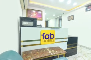 A reception desk with a sign reading 'fab HOTELS' and a marble-topped bench.