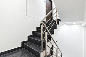 A staircase with black steps and a metal handrail, leading to a door.