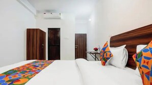 Habitación de hotel con cama, dos armarios, una mesita con un florero y un equipo de aire acondicionado en la pared.