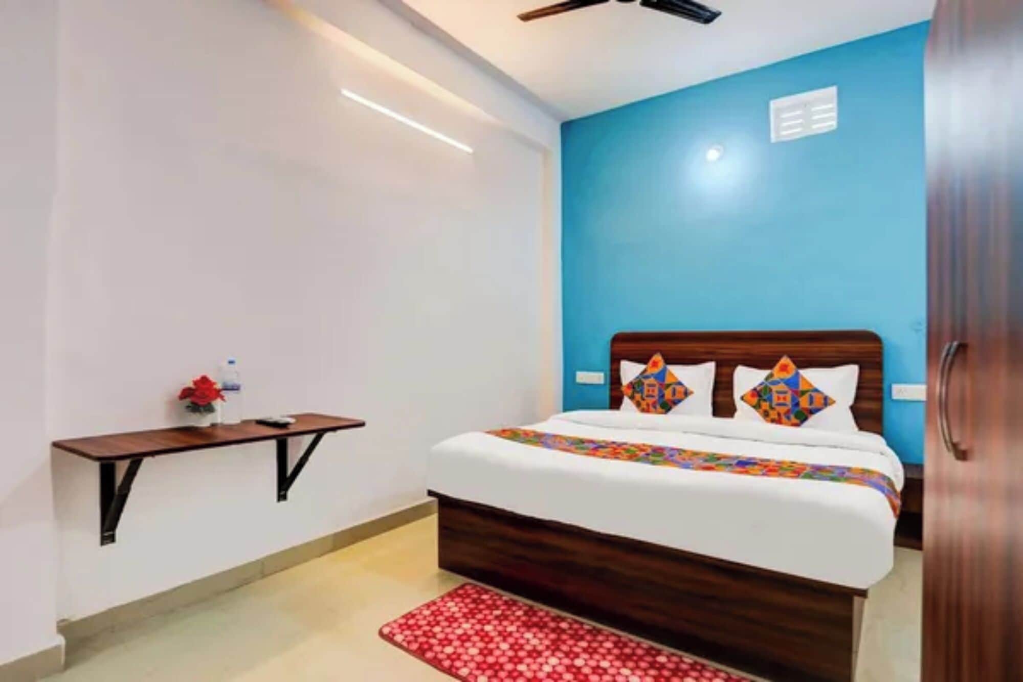 Une chambre à coucher avec un lit, une table de chevet, un tapis rouge et un mur bleu.