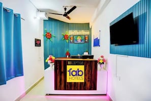 Una mesa de recepción con un cartel que dice 'fab hotels' y un cartel con el texto 'Hotel Ranch Retreat' encima.
