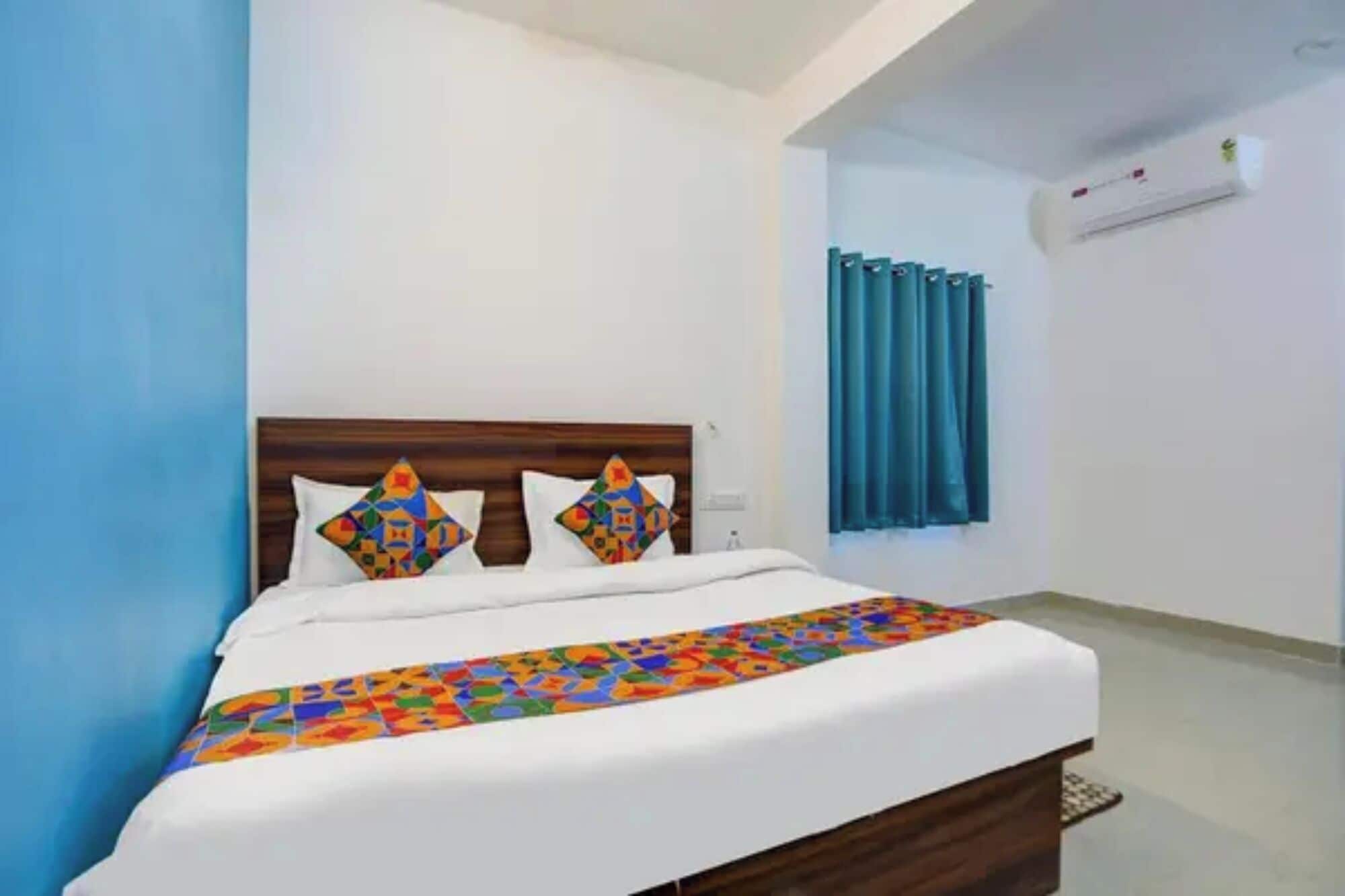 Habitación de hotel con una cama, cabecera, ventana con cortinas y equipo de aire acondicionado.